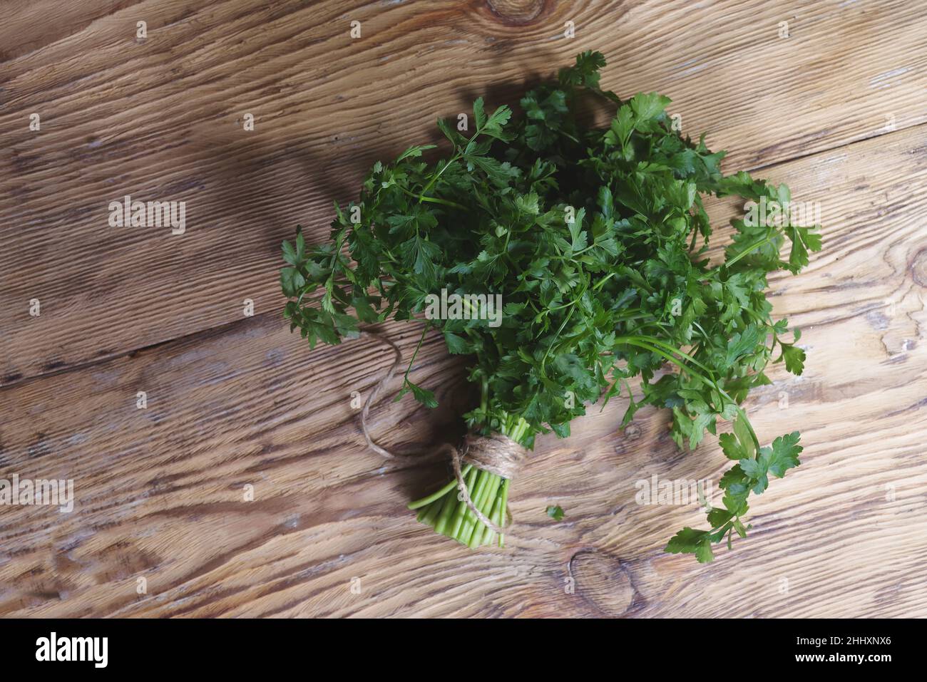 Parsley on wooden table background. Fresh raw parsley plant top view. Parsley indispensable source of vitamins A, C, K, B1, B2, PP, E, C Stock Photo