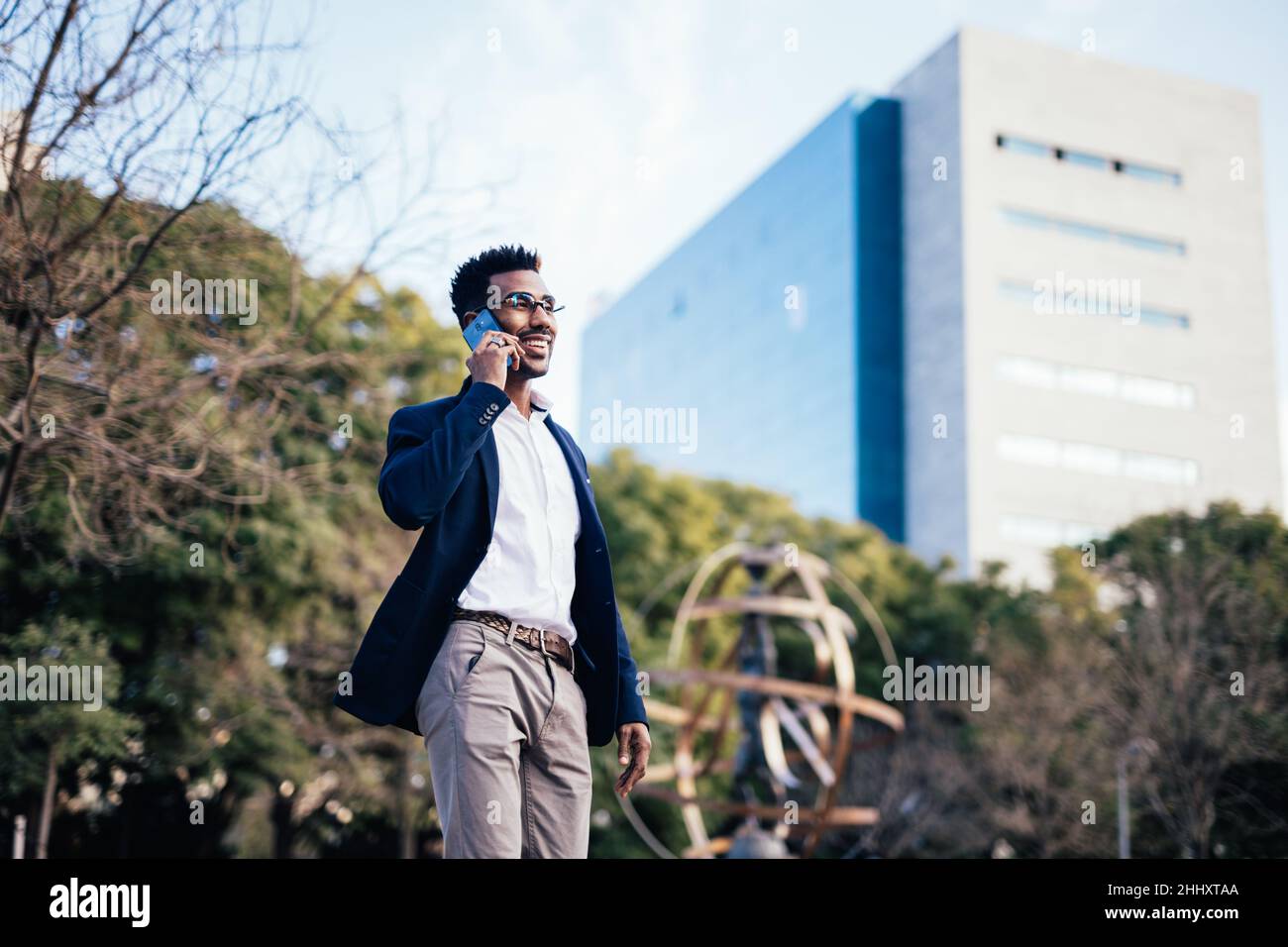 Business black man walking down the street while using his smartphone Stock Photo