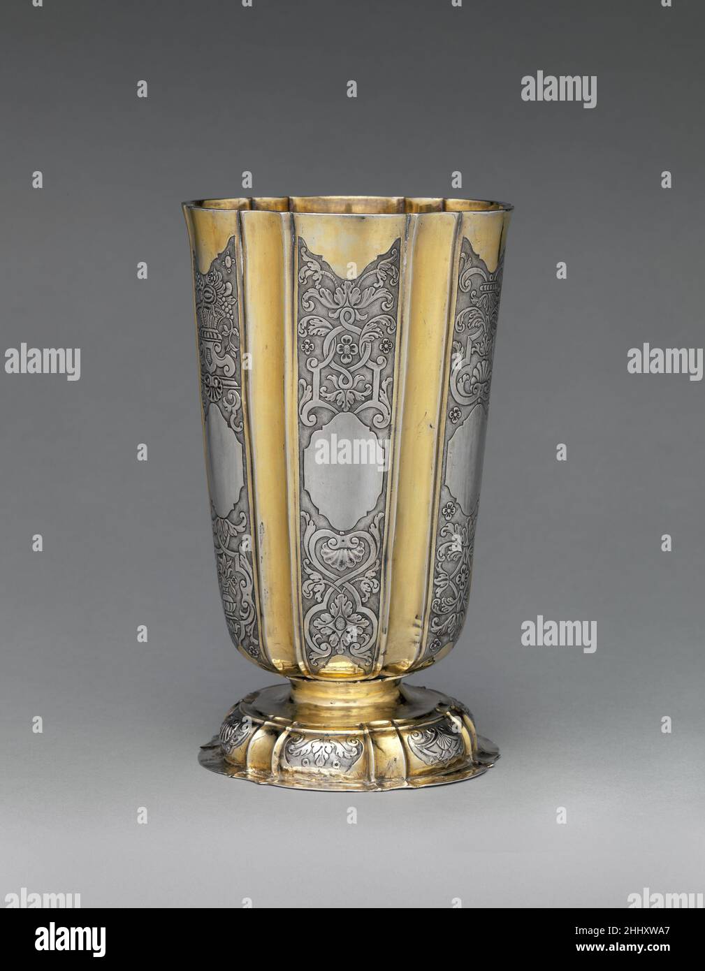Beaker ca. 1730–50 Georgius Olescher Jr. An elegant rhythm is created in this beaker by alternating gilded vertical concave flutes with silver panels containing finely embossed and chased ornament on a matte ground. Georgius Olescher Jr., the maker here, was probably inspired by the work of Michael II May, who spent several years in France becoming familiar with Regence ornaments, returning to Brassó by December 1731. Other Transylvanian beakers are similarly decorated, including examples with this typical bell-shaped form. And it was May who produced several such large beakers, all of which a Stock Photo