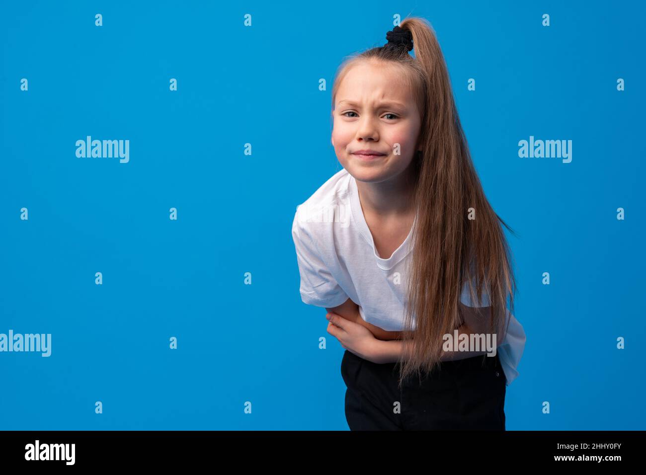 Young girl with bellyache isolated on a blue background Stock Photo - Alamy