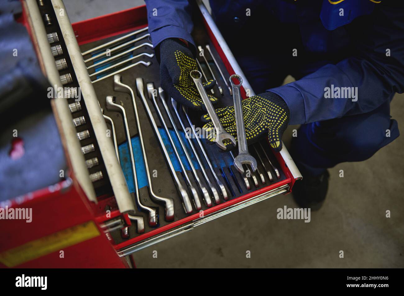 Overhead view of auto mechanic holding wrenches above a set of tools