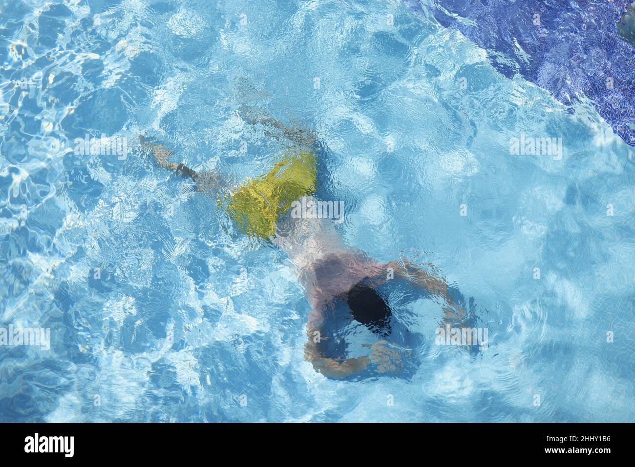 Male person in swimming pool floating on water on belly, diving on