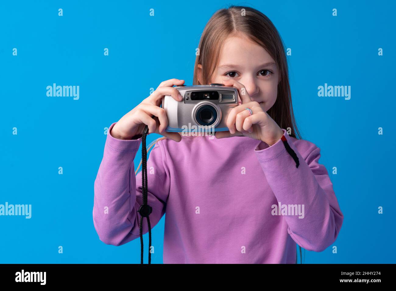 Portrait of a little girl with camera against blue background Stock ...