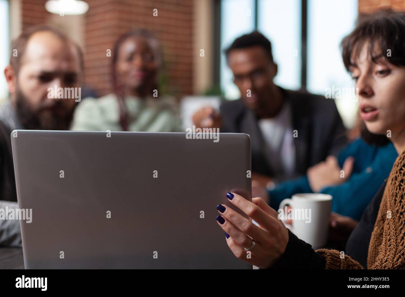 Multiracial businesspeople looking at laptop screen analyzing company turnover working at marketing strategy during business meeting in startup office. Multiethnic team brainstorming ideas Stock Photo