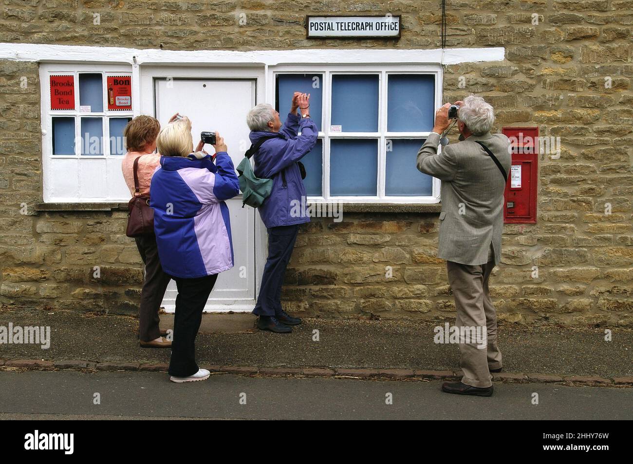 Four amateur photographers taking shots of the historic Postal Telegraph Office in the village of Wadenhoe, Northamptonshire, UK Stock Photo