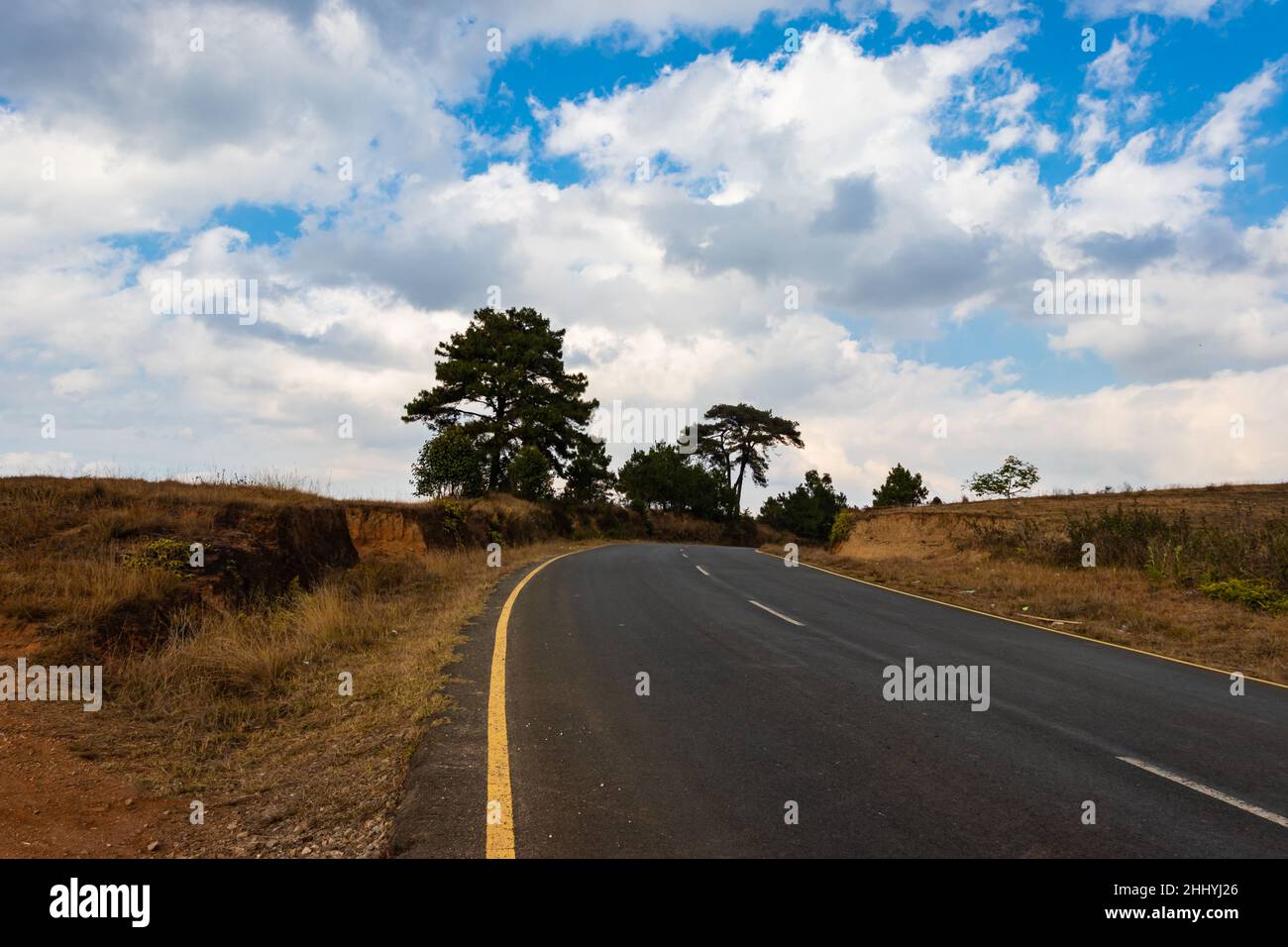 isolated countryside tarmac road with bright blue sky at morning from flat angle image taken on sohra fall meghalaya india. Stock Photo