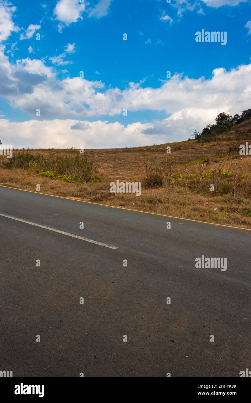 isolated countryside tarmac road with bright blue sky at morning from flat angle image taken on sohra fall meghalaya india. Stock Photo