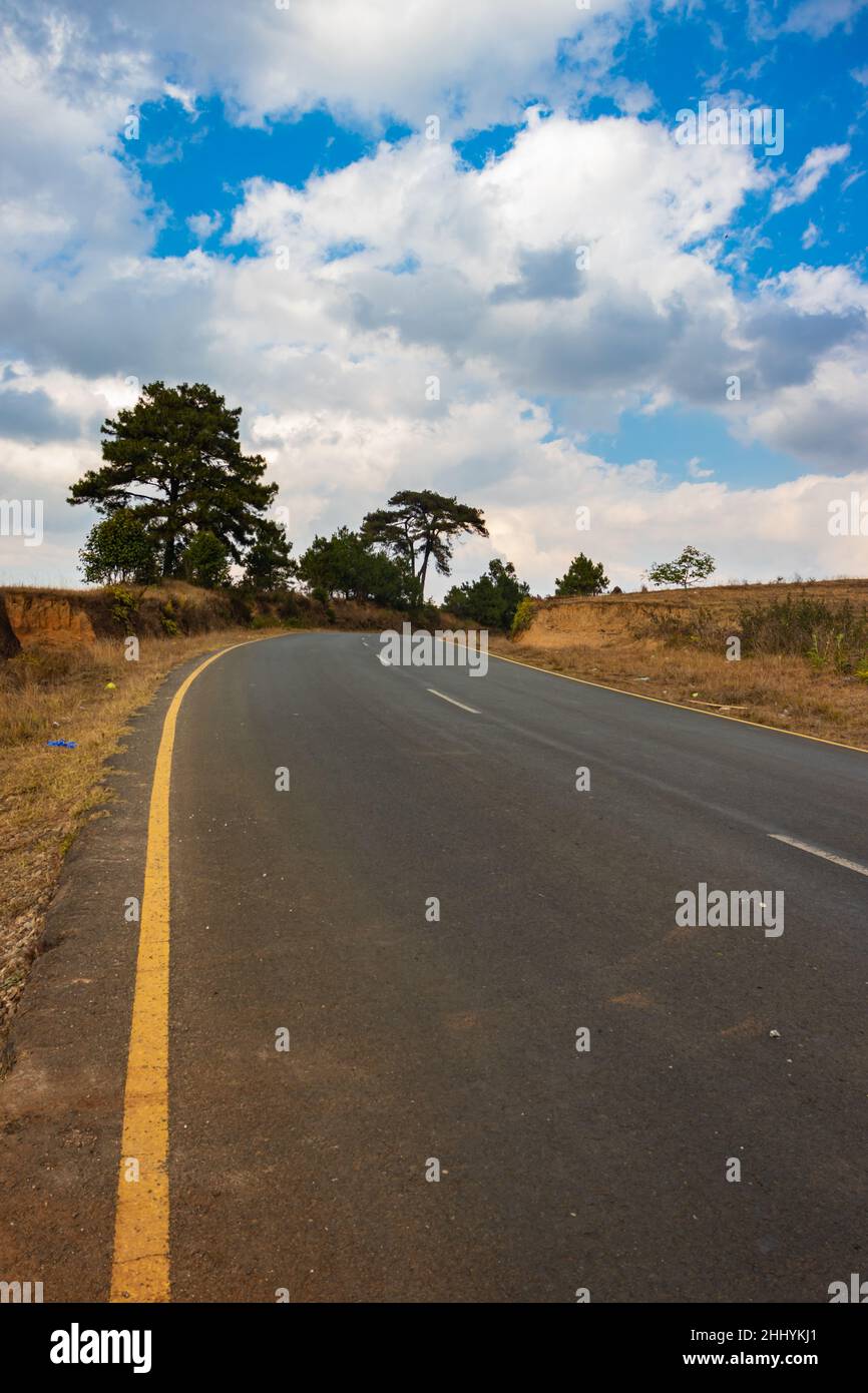 isolated countryside tarmac road with bright blue sky at morning from flat angle image taken on sohra fall meghalaya india. Stock Photo