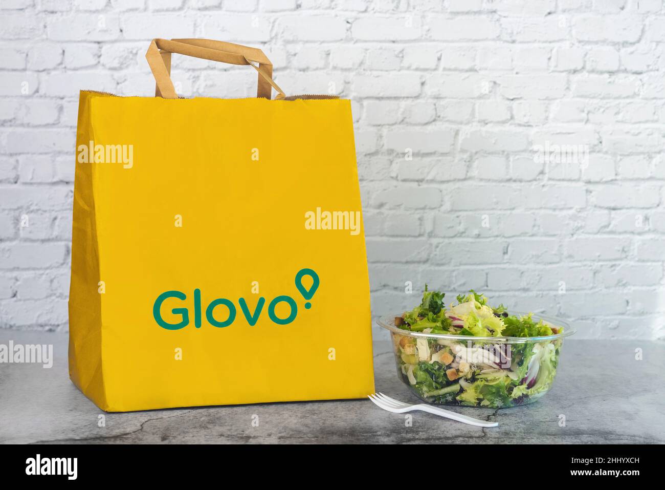 Glovo food paper delivery bag next to a salad on a table Stock Photo