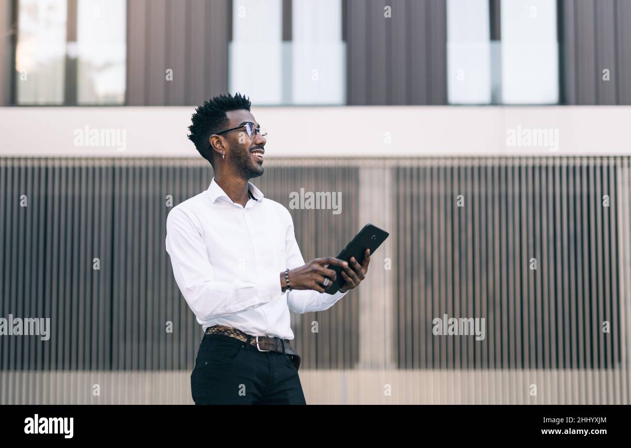 Smiling young black businessman using tablet outdoors Stock Photo