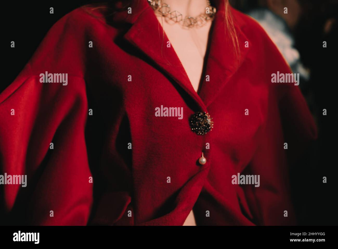 Part of a female body dressed in an elegant red jacket with golden buttons. Women's fashion and accessories Stock Photo
