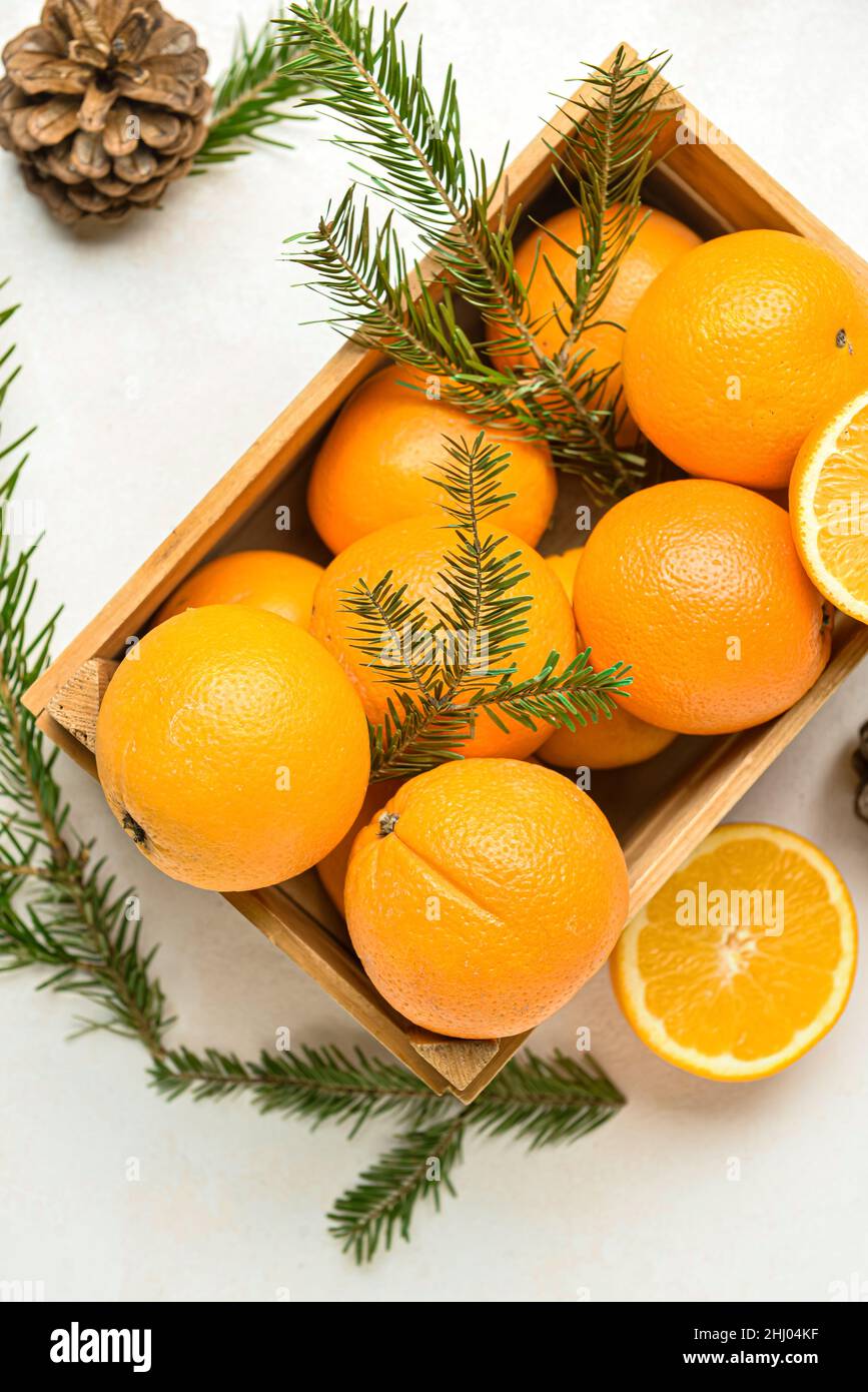 Wooden box with fresh oranges and fir branches on white background ...