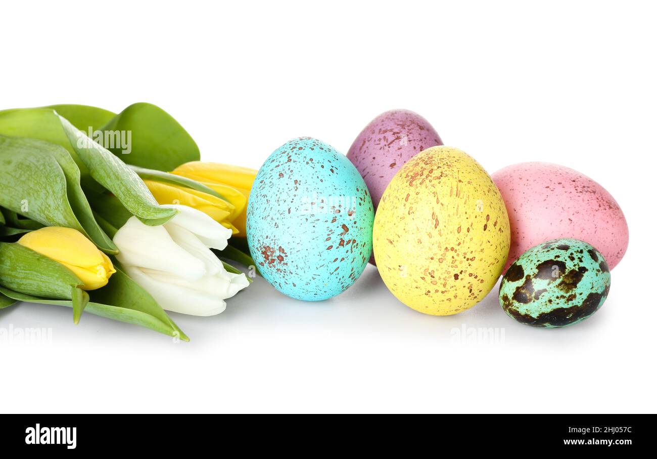 Beautiful Easter eggs and tulips on white background, closeup Stock Photo