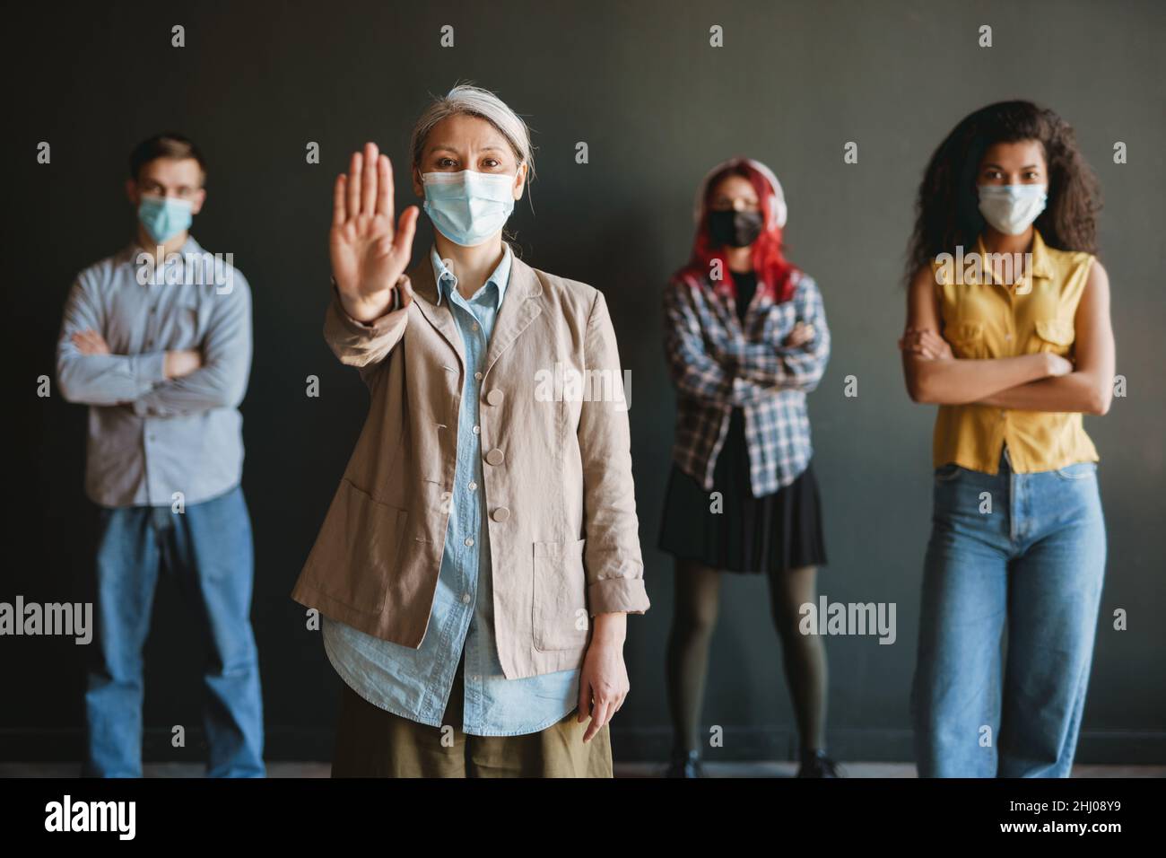 Mature woman in face mask showing stop gesture at camera isolated over ...