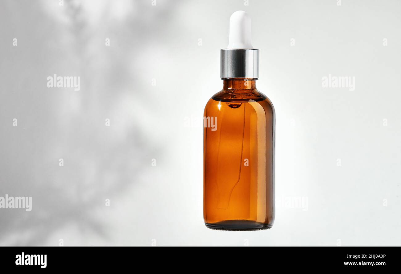 Essential oil in glass bottle with dropper isolated on a gray background with clipping path. Cosmetic medical beauty product for aromatherapy. Alterna Stock Photo