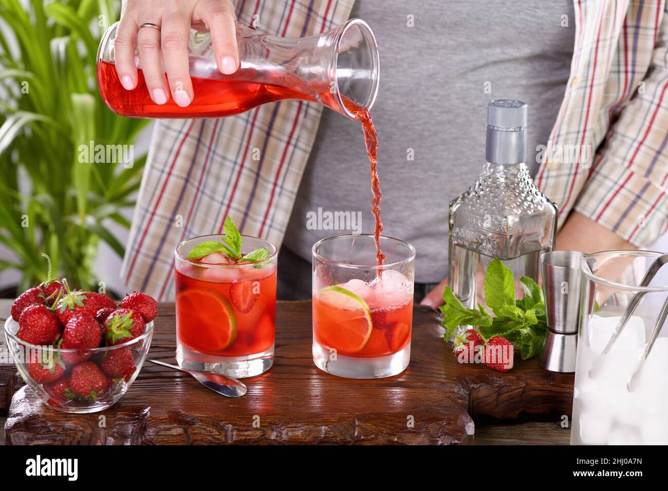 The bartender prepares a refreshing strawberry mojito cocktail with ice, fresh mint and lime. Great idea for a picnic or summer party. It may contain Stock Photo