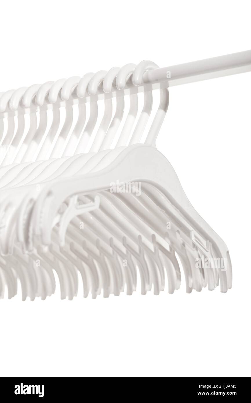 White plastic hangers for clothes hanging on rod from clothing rack