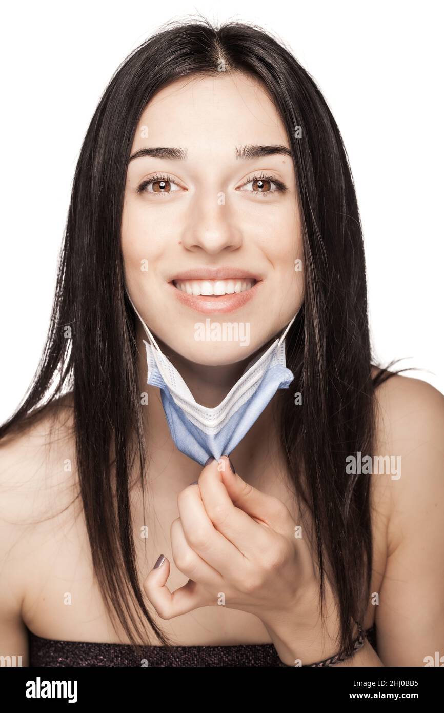 Happy girl pulling away medical face mask. Portrait against white background. Stock Photo
