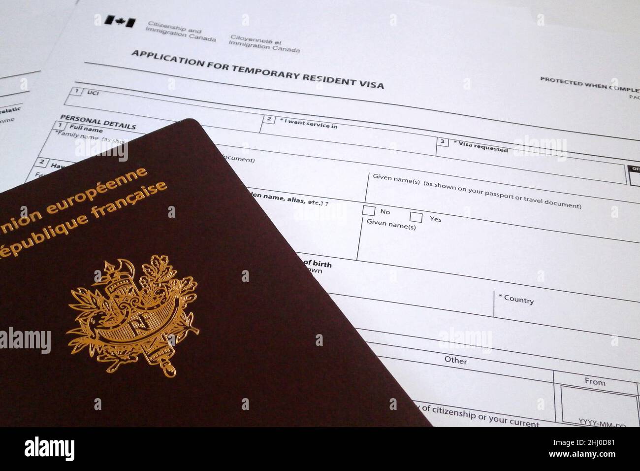 A French passport on the top of an Canadian application form to obtain a Temporary resident visa. Stock Photo