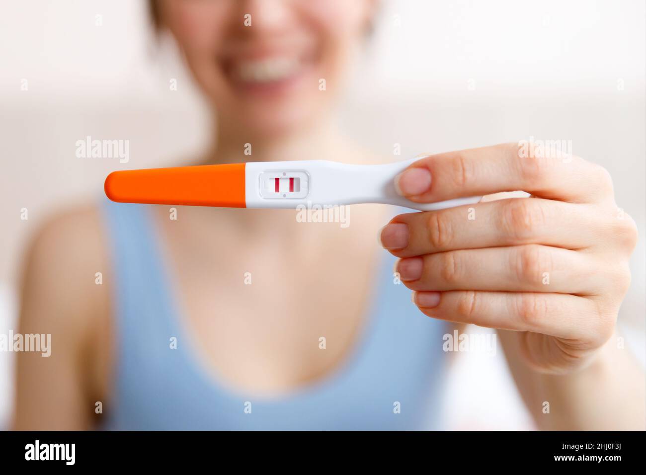 A happy young woman holds a positive pregnancy test in her hand, the concept of a long-awaited pregnancy. Stock Photo