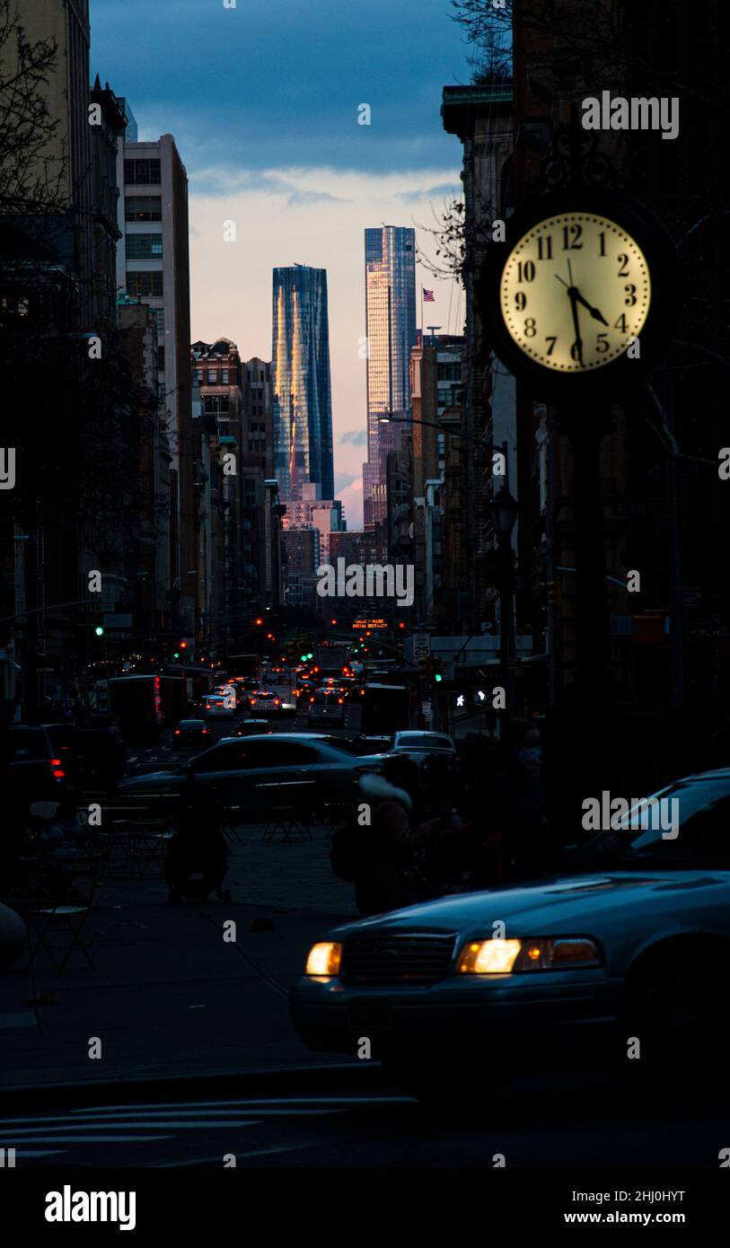 Faszinierender Kontrast zwischen den dunklen Gassen Manhattans und zwei Hochhäusern im Abendlicht Stock Photo