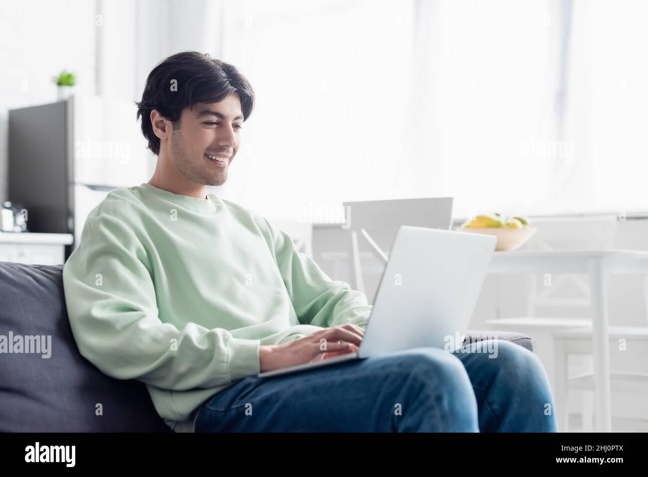 pleased man using laptop while sitting on couch at home Stock Photo