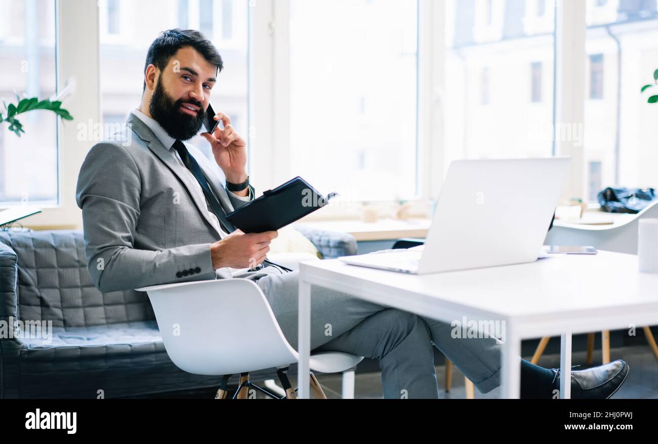 Positive bearded entrepreneur talking on phone Stock Photo