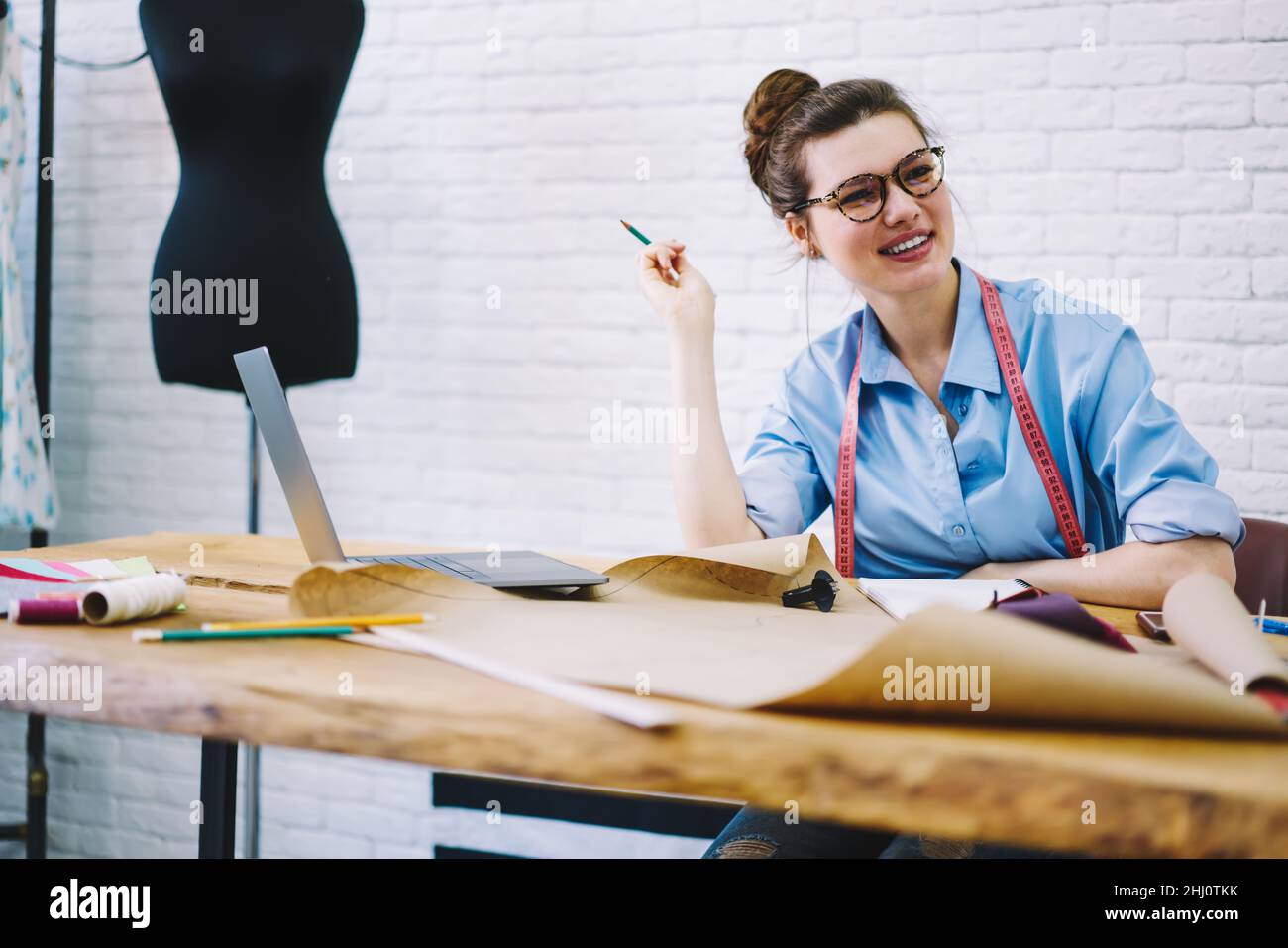 Happy young dressmaker working in sewing studio Stock Photo