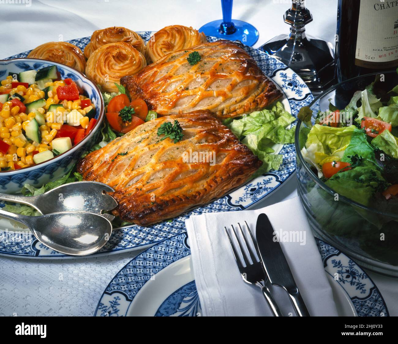 Two lattice topped slices on a blue & white plate bowl of salad sweetcorn cucumber, tomatoes, red peppers lettuce, parsley knife & fork white napkin Stock Photo