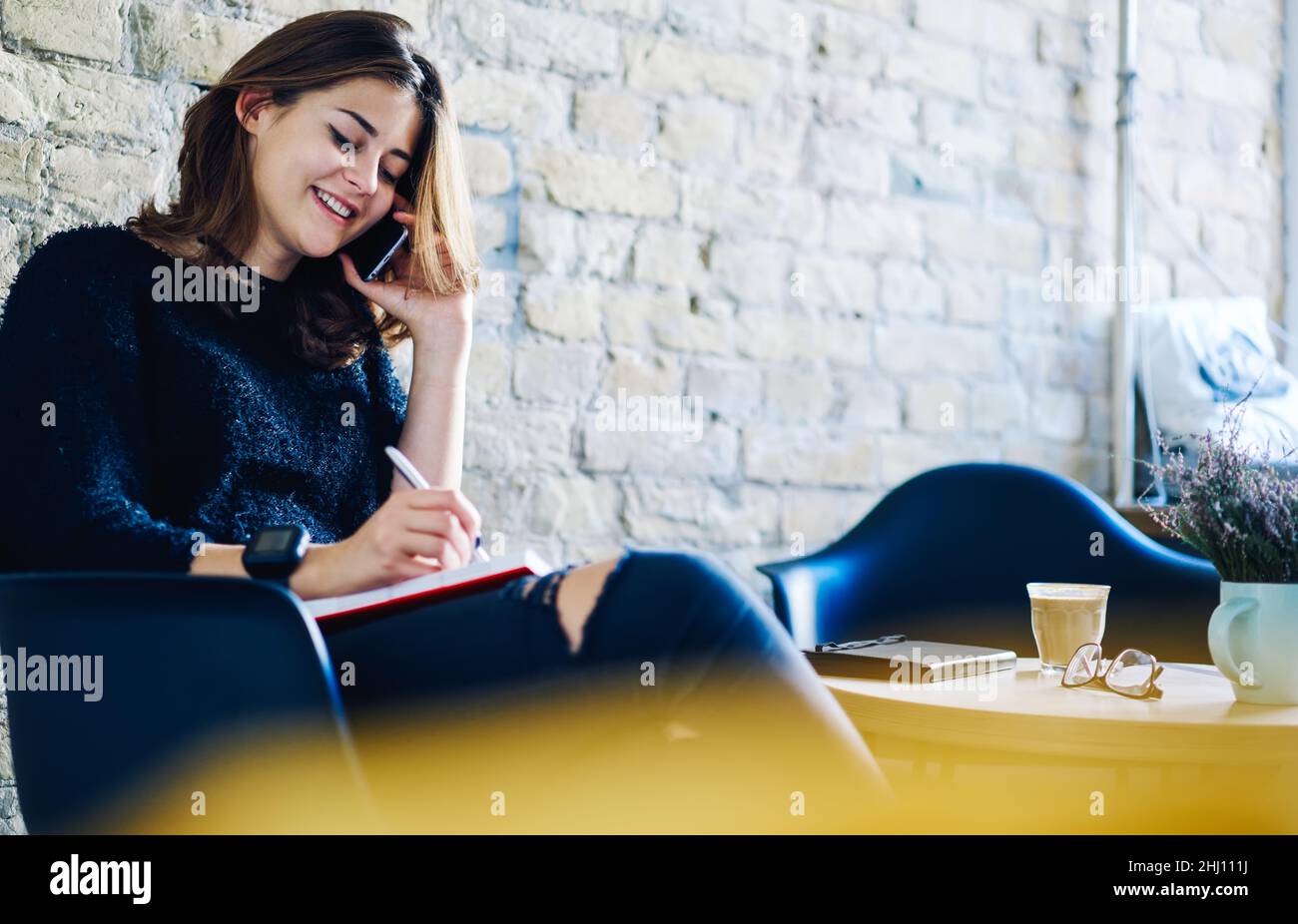 Happy lady sitting in cafe with notebook and smartphone Stock Photo