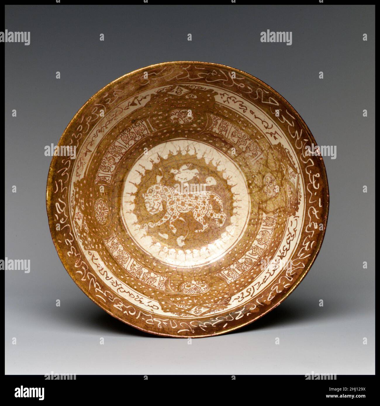 Bowl with Leopard early 13th century The lion was a symbol of power, strength, and royalty. Its reigning planet is the Sun, which is shown here as a circular disk against which the whimsically spotted lion is set. The bowl was made in Kashan, in central Iran, where the technology for making luster-glazed ceramics was introduced in the early twelfth century, with the arrival of the potters from Egypt who carried the secret knowledge for creating this decorative effect.. Bowl with Leopard. early 13th century. Stonepaste; luster-painted on opaque white glaze. Attributed to Iran, Kashan. Ceramics Stock Photo