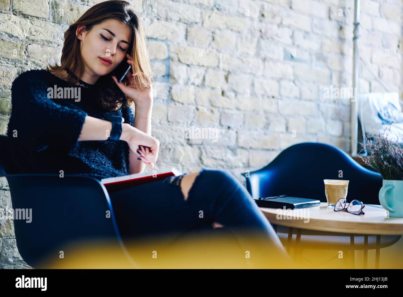 Female freelancer sitting in cafe with smartphone and notebook Stock Photo