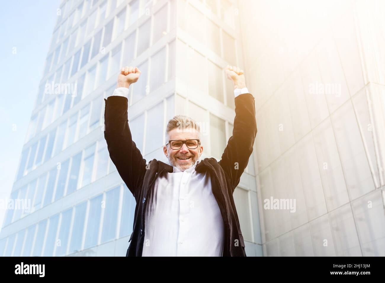 Low angle view of excited senior businessman holding his arms raised ...