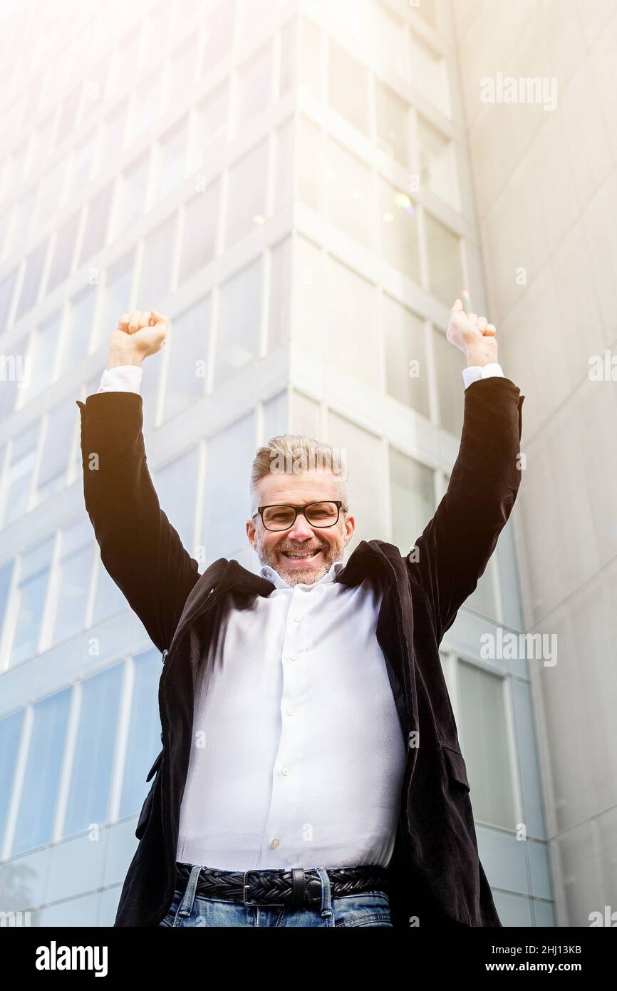 Low angle view of excited senior businessman holding his arms raised ...