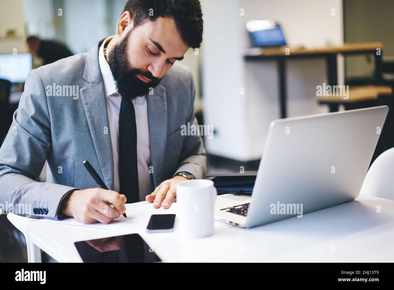 Businessman writing notes while working in office Stock Photo