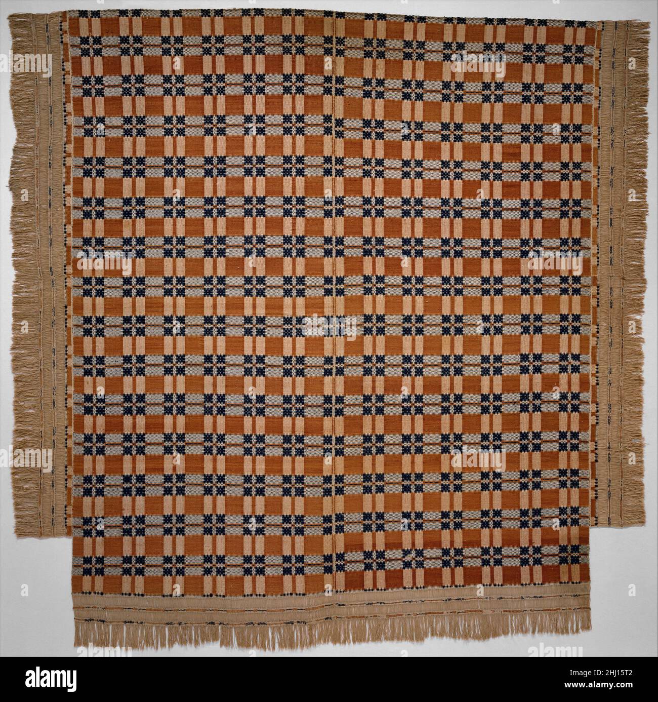Coverlet ca. 1825 American This overshot coverlet is woven of undyed cotton and blue and orange wool in two panels and seamed at the center. There is an applied woven fringe along each side and along the bottom edge. The piece is T-shaped to accommodate bedposts.. Coverlet  13635 Stock Photo