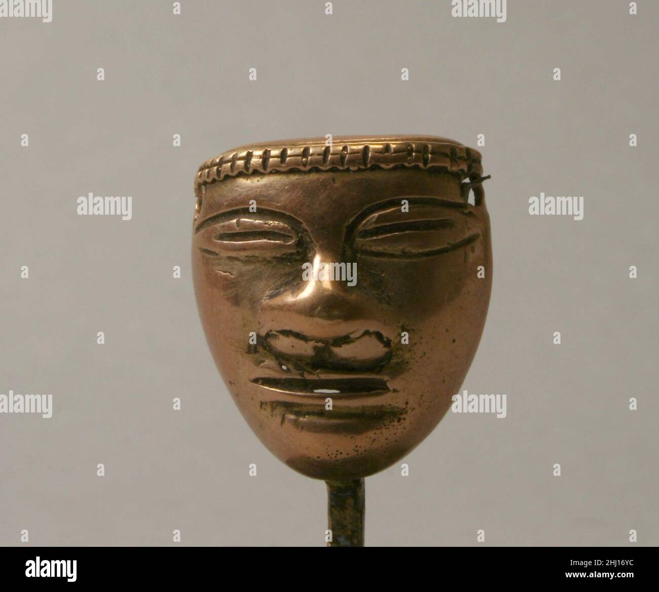 Anthropomorphic Bead 300 B.C.–A.D. 700 Early Quimbaya This small metal bead showing a human face was made as part of the Quimbaya tradition of metalworking. The area related to the Quimbaya tradition includes much of the Cauca Valley and part of the Central Cordillera of Colombia. A person may have worn this bead along with other beads and ornaments as part of a necklace, or the bead adorned another object or material. On the obverse, there is a narrow band around the top of the head that consists of two rows of rectangular blocks. The eyes are elliptical, but the lines that form them are disc Stock Photo