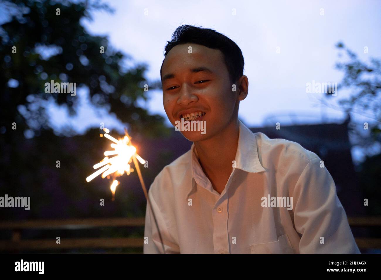 Smiling boy lighting fireworks at night during the celebration Stock