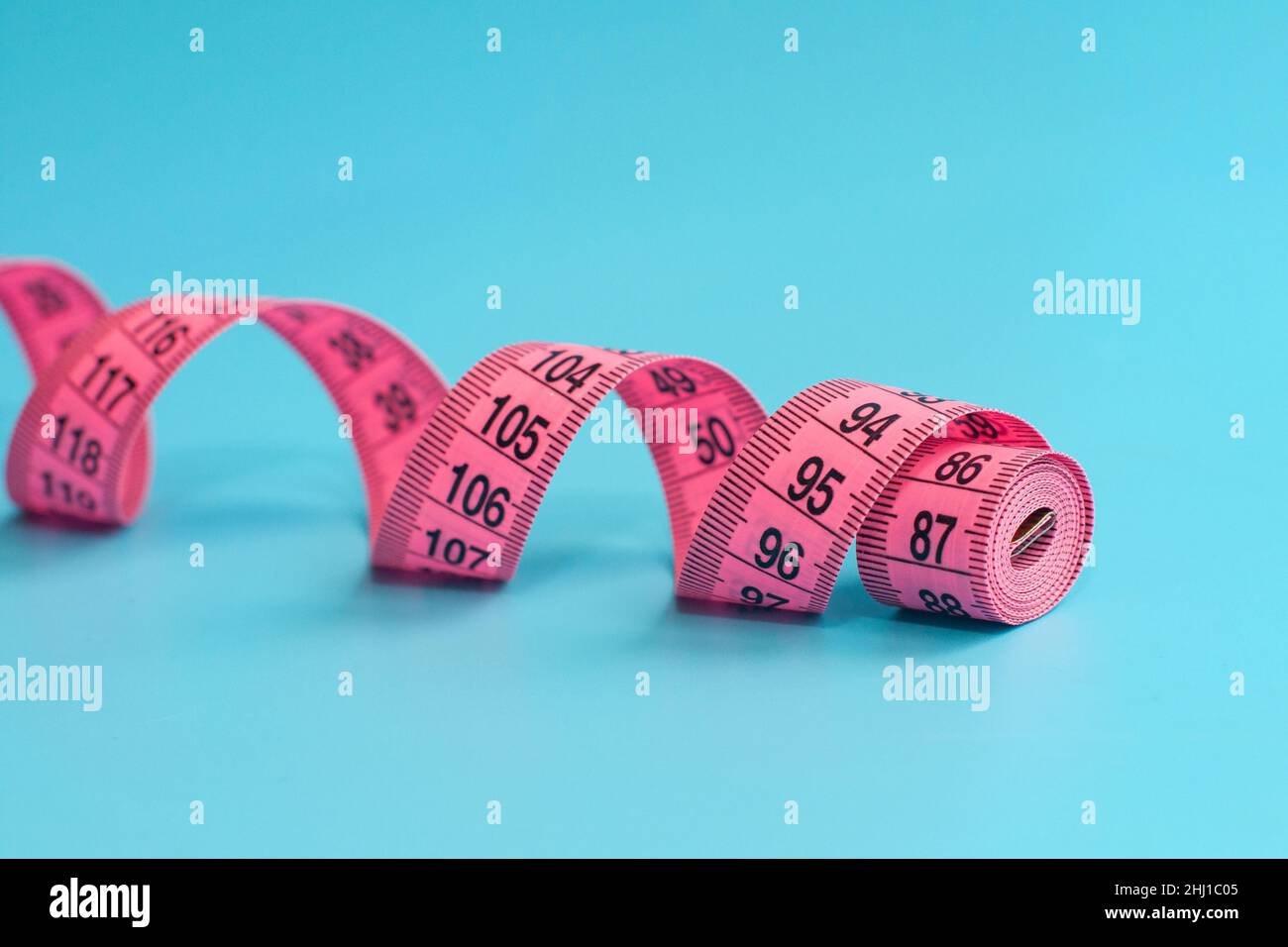 Pink centimeter tape measure on blue background Stock Photo - Alamy