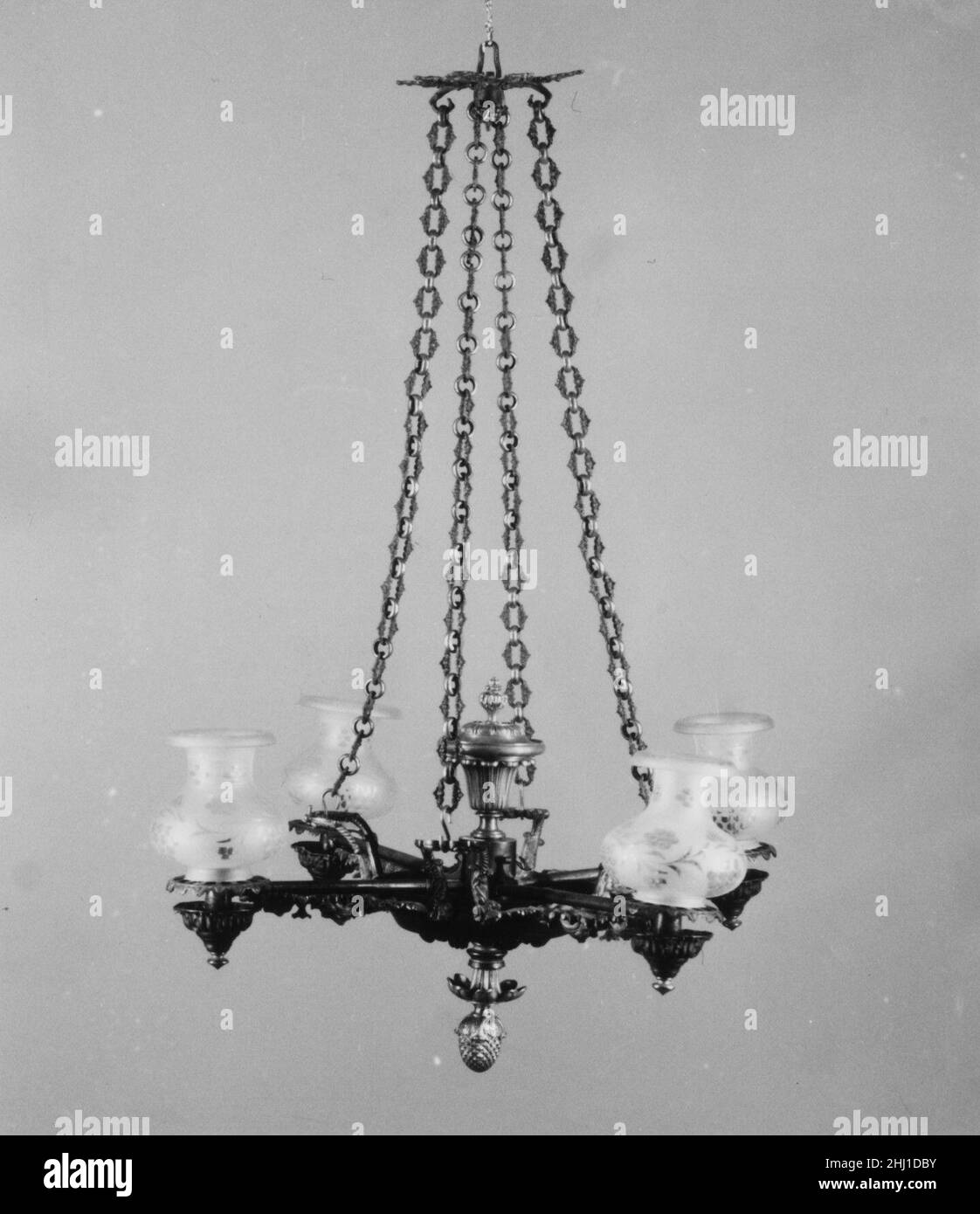 Chandelier ca. 1845 Clark, Coit and Cargill This chandelier with four burners and an urn-shaped oil reservoir is one of the few surviving examples documented to a New York retailer. Thomas Webster illustrates a closely related example, which he calls a 'suspended Argand lamp,' in his 'Encyclopaedia of Domestic Economy' (1845), describing 'the chains very ornamental, and the branches concealed by very rich brass work.'. Chandelier. American. ca. 1845. Bronze. Made in New York, New York, United States Stock Photo