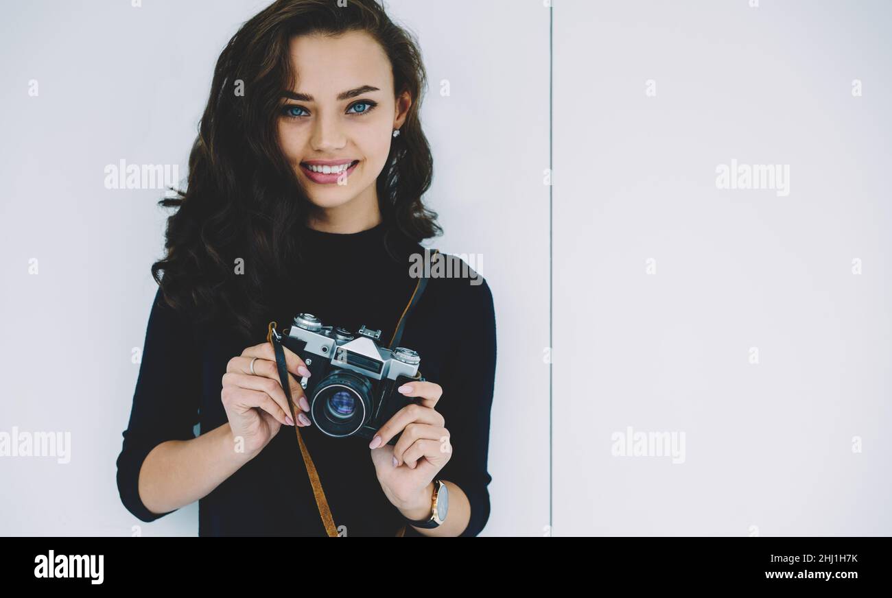 Young brunette standing on white background with photo camera Stock Photo