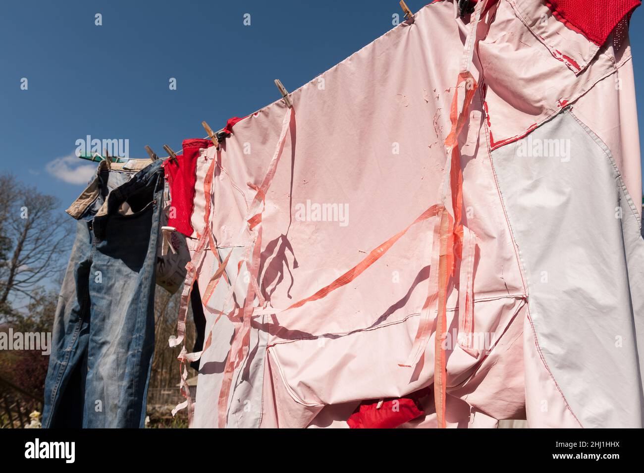 Wrong wash cycle and heat setting on washing cycle leading to waterproofing coating of rain jacket being ruined flaking off seams pleats falling off Stock Photo