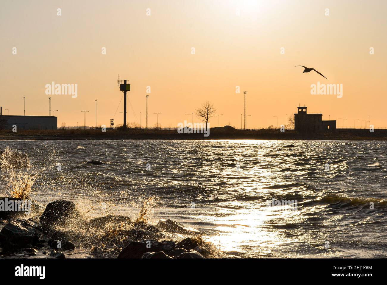 Waves and splashes on the sea against the sunset in the harbor Stock Photo