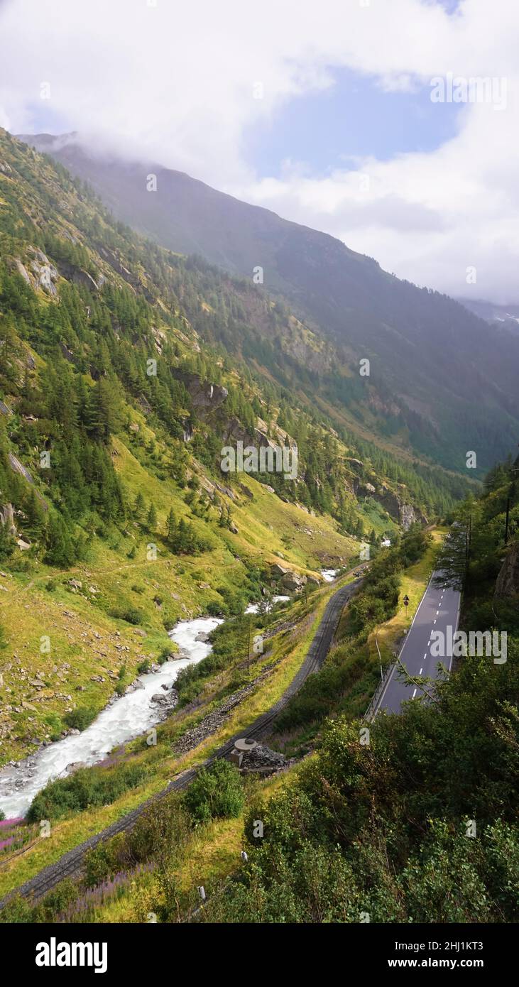 Mountain valley in Switzerland, river, road, dense forest and fog Stock Photo