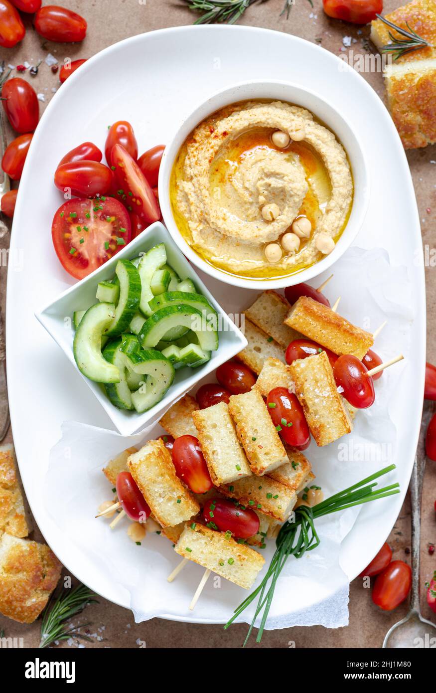 An appetizer of hummus, toasted bread and vegetables Stock Photo