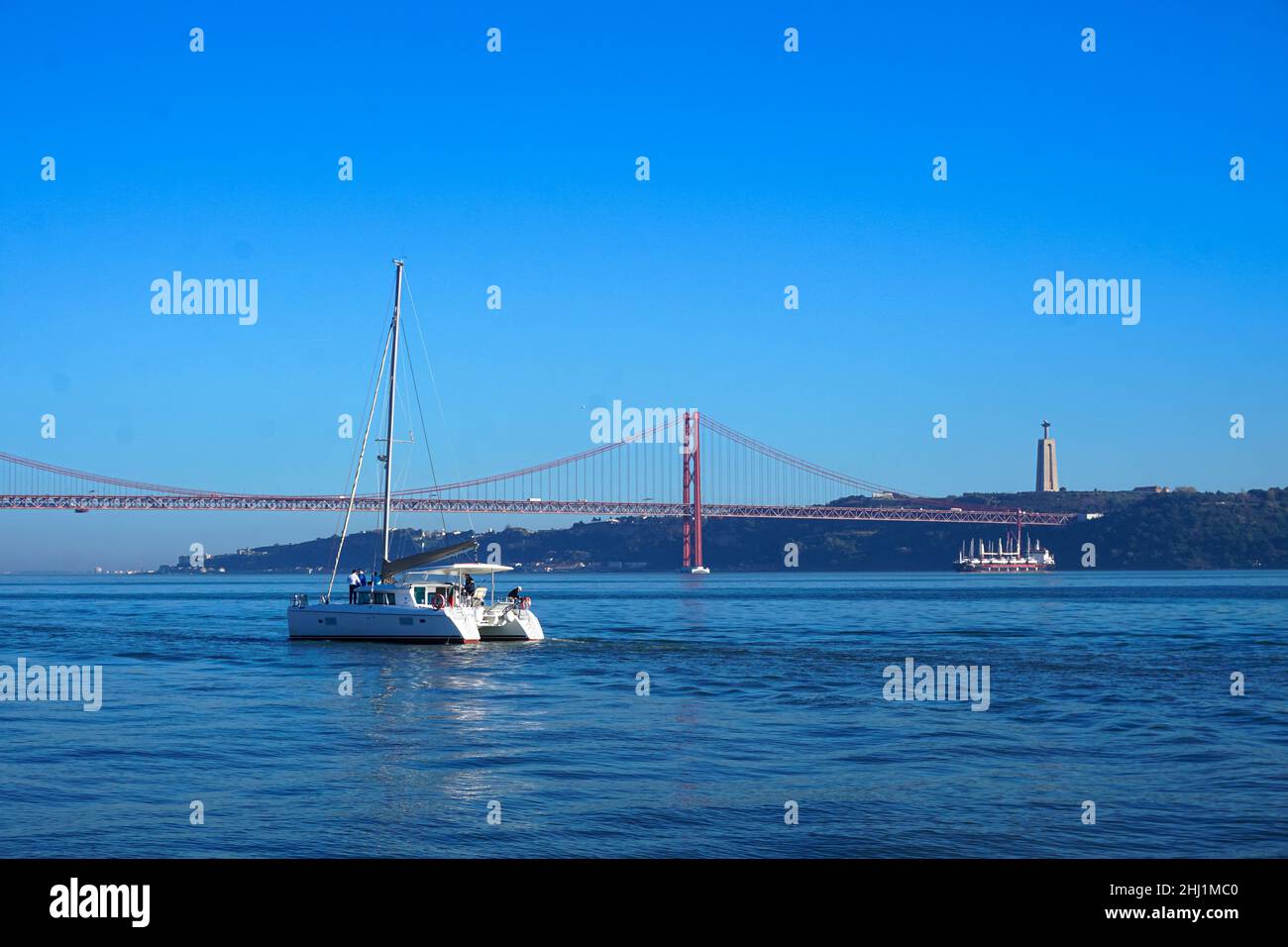 White yacht against the background of the underwater bridge in Lisbon, Portugal Stock Photo