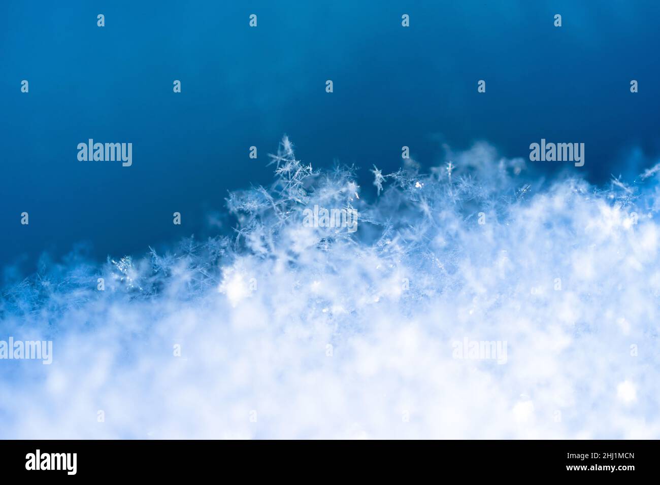Lots of little snowflakes in the snow, blue background, close up Stock Photo