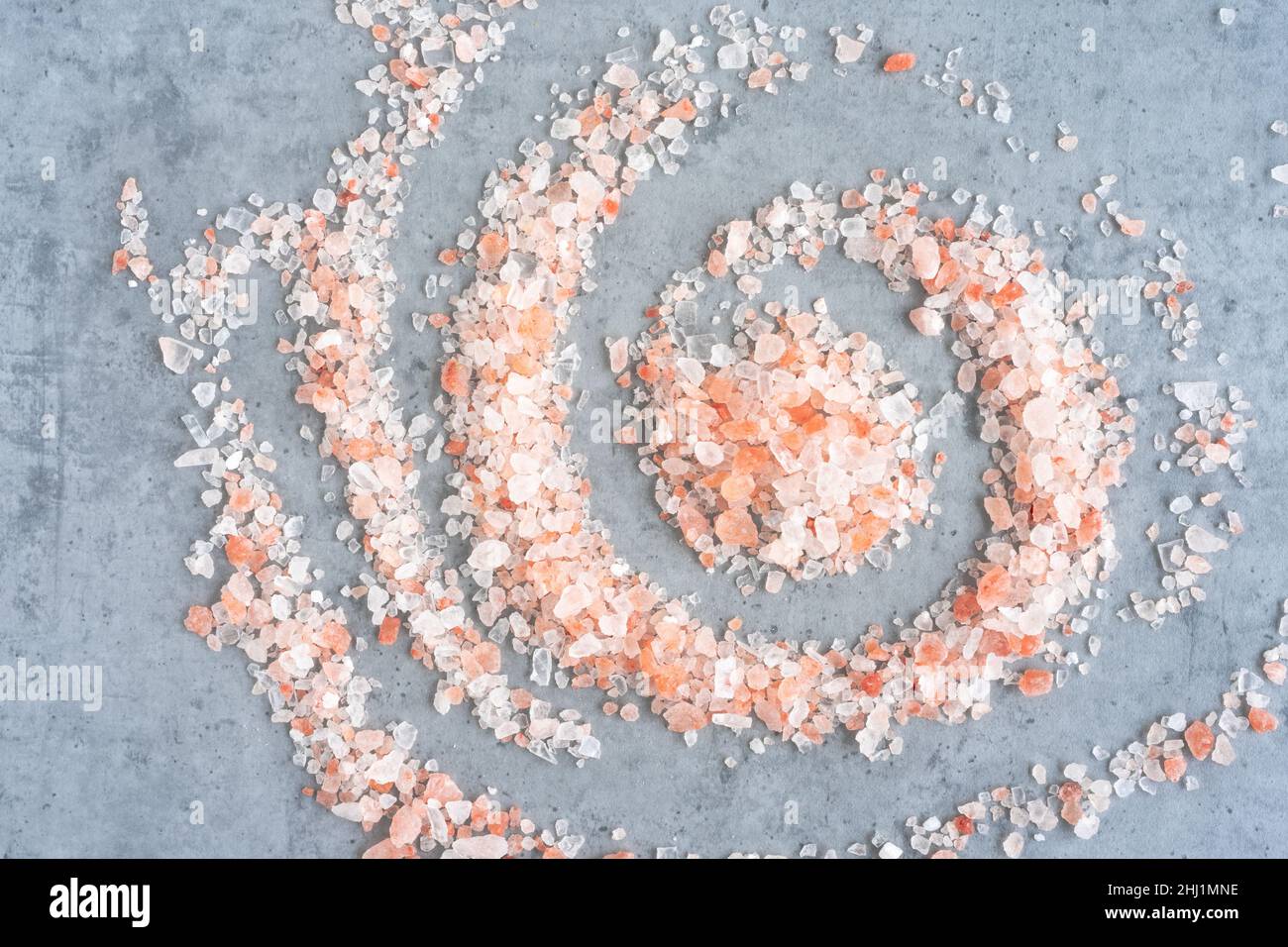 Himalayan salt scattered in a spiral shape on a gray background, top view Stock Photo