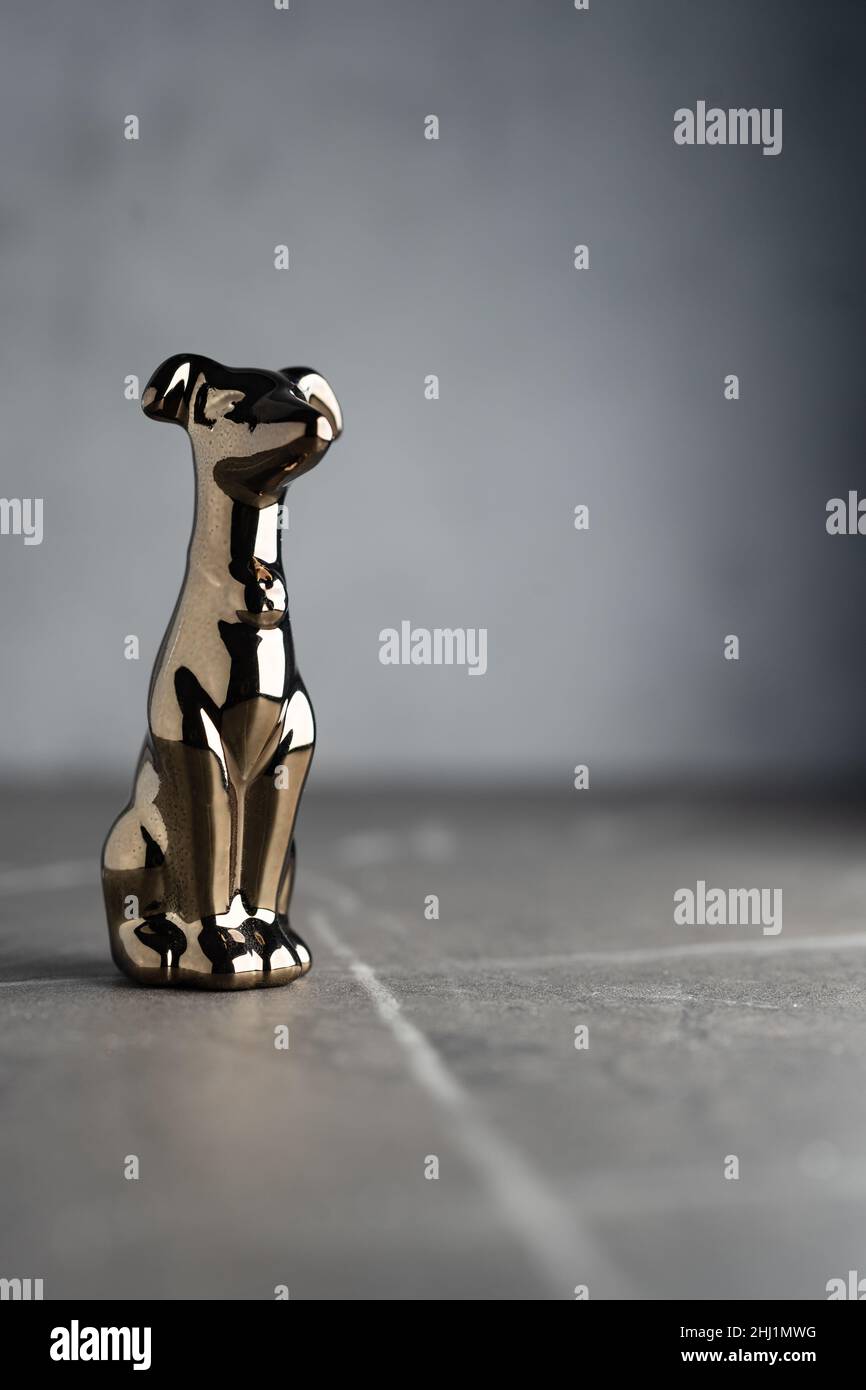 Сhrome-plated metal statuette of a dog, isolated on a dark neutral background Stock Photo