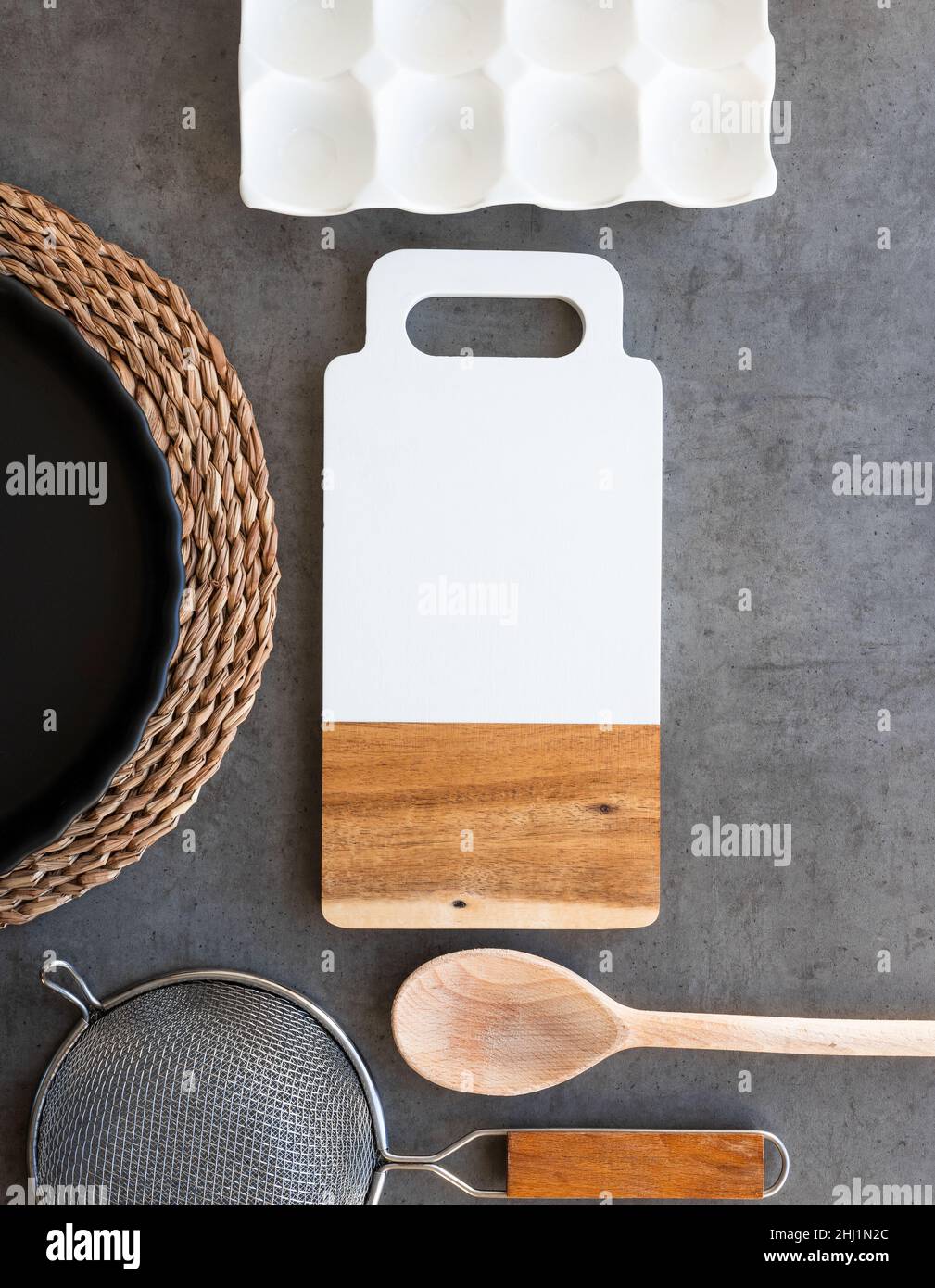 Kitchen utensils on dark gray background, board, sieve, spoon, baking dish Stock Photo